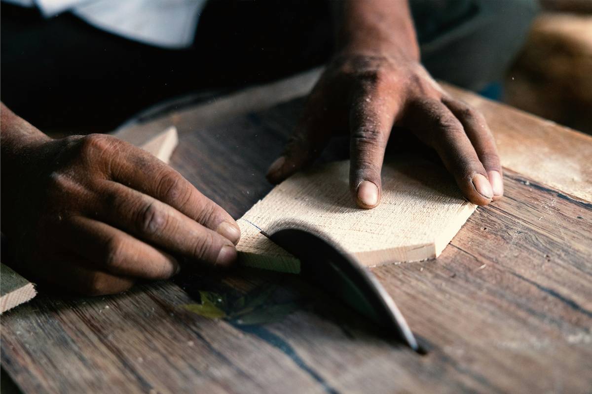 Hand applying food safe wood preservative to a wooden cutting board with brush